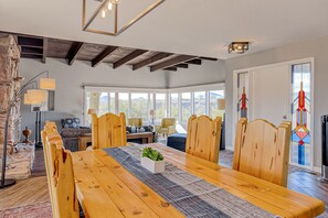 A spacious dining area with a wooden table and chairs, a small plant centerpiece, and large windows offering a view of the outdoors. - Dog-friendly mountain-view home with private pool, outdoor lounging & W/D (Cave Creek)