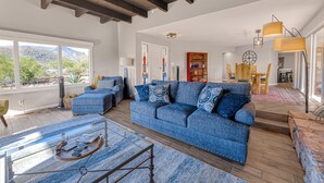 A spacious living room with a blue sofa, a glass coffee table, and a wooden floor. - Dog-friendly mountain-view home with private pool, outdoor lounging & W/D (Cave Creek)