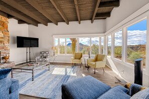 A spacious living area with a stone wall, a flat-screen TV, and a large window offering a mountain view.