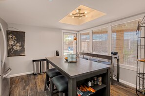 Une cuisine moderne dotée d’un îlot central, d’un four encastré et d’une fenêtre donnant sur l’extérieur.