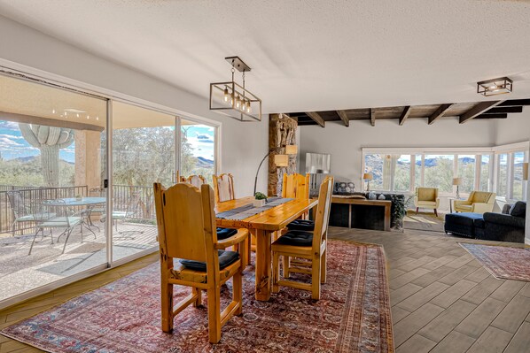 A spacious living area with a wooden dining table, chairs, and a large rug. There is a sliding glass door leading to an outdoor patio. - Dog-friendly mountain-view home with private pool, outdoor lounging & W/D (Cave Creek)