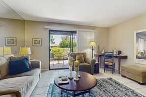 A living room with a sofa, coffee table, and a dining area with a table and chairs. - Charming Palm Springs Condo with Breathtaking Views & Resort-Style Comforts. (Palm Springs)