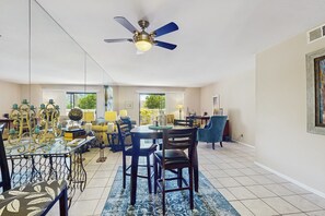 A spacious dining area with a round table, dark wooden chairs, and a blue patterned rug. A ceiling fan is visible above the table. - Charming Palm Springs Condo with Breathtaking Views & Resort-Style Comforts. (Palm Springs)
