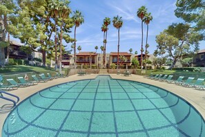 A large outdoor swimming pool with a grid pattern, surrounded by lounge chairs and palm trees. - Charming Palm Springs Condo with Breathtaking Views & Resort-Style Comforts. (Palm Springs)