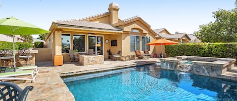 A residential property with a swimming pool, outdoor seating, and a covered patio area.