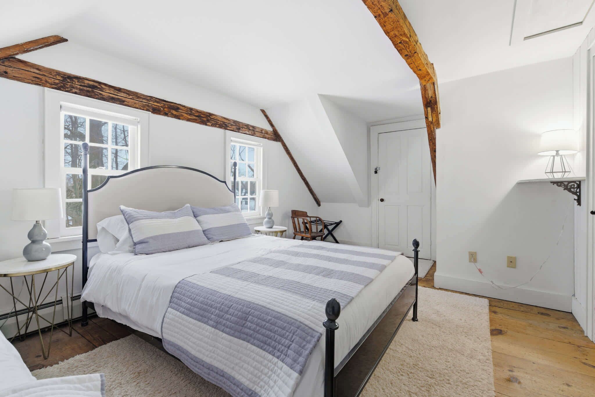 Une chambre à coucher avec un lit, une table de chevet, une lampe et une fenêtre.