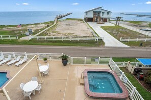 A pool area with lounge chairs, a hot tub, and a view of the ocean. - Windward 312 at Laguna Reef - Bay Views (Rockport)