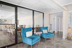 A modern hotel lobby with two blue armchairs, a round table, and a glass partition. - Windward 312 at Laguna Reef - Bay Views (Rockport)