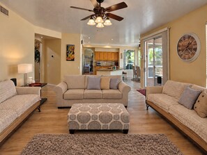 A spacious living room with a ceiling fan, a patterned ottoman, and a large clock on the wall. - Beautiful home with private pool, W/D, central AC & great locale - dog-friendly (Mesa)