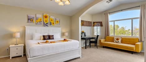 A bedroom with a bed, a desk, a chair, a yellow sofa, and a ceiling fan.