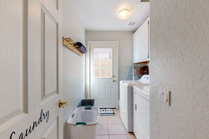 Un cuarto de lavado con una puerta que indica "Laundry", una lavadora, un tendedero y una cesta de ropa.