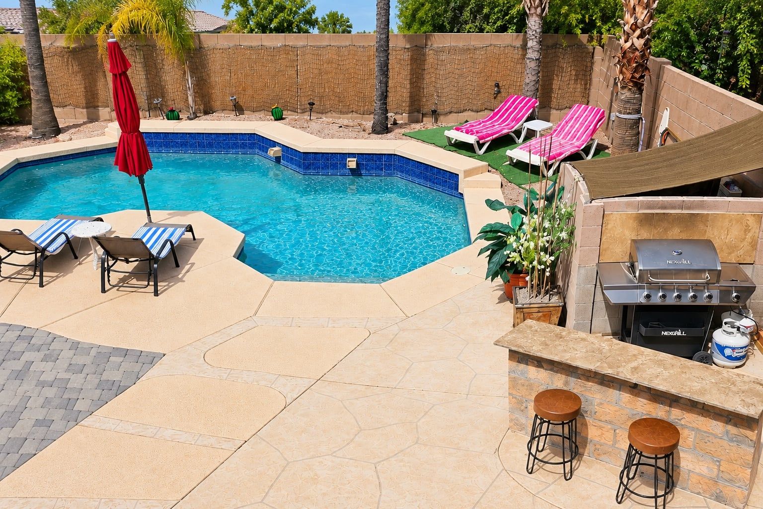 A swimming pool with lounge chairs and a barbecue area.