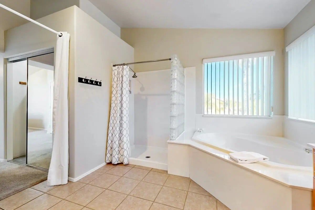 Une salle de bain avec une douche, une baignoire et une fenêtre.