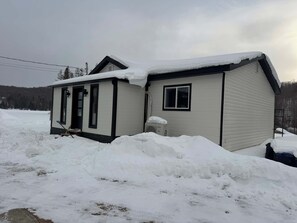 A single-story house with a snow-covered roof and a small porch.