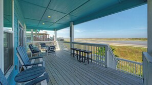 A covered porch with outdoor seating, a view of the beach, and a building in the background. - La Sirena by Avantstay Communal Pool + Covered Lounge + Marsh Views + Near Port A Beach (Port Aransas)