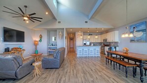 A spacious living area with a sofa, a coffee table, a TV, and a ceiling fan. - La Sirena by Avantstay Communal Pool + Covered Lounge + Marsh Views + Near Port A Beach (Port Aransas)