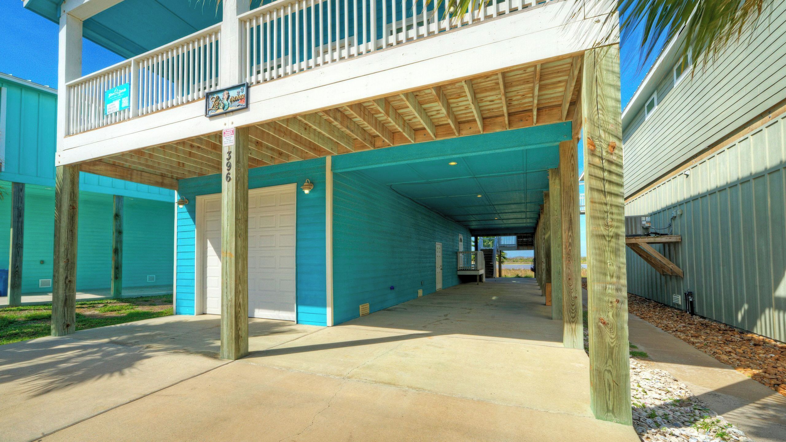 A covered outdoor area with a wooden deck, a garage door, and a sign for 'Lo & Behold'.