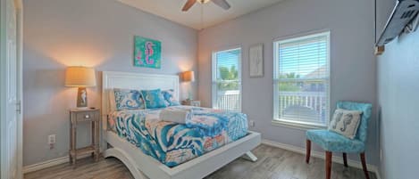 A bedroom with a bed, two bedside tables, a ceiling fan, a window, and a chair.