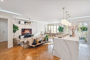 Un salon moderne avec une cheminée, un coin repas et une cuisine.