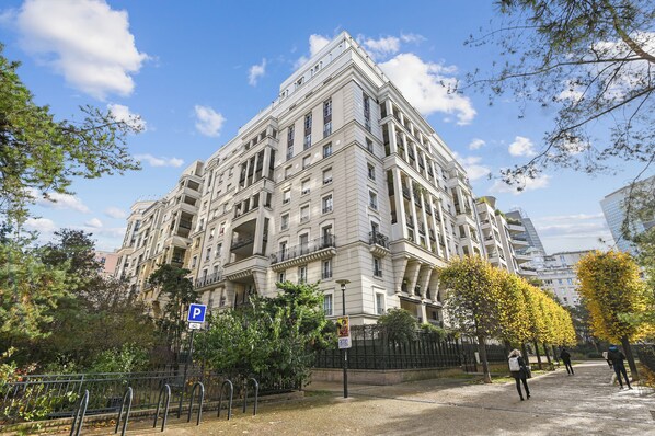 Un immeuble à plusieurs étages de style architectural classique, doté de balcons et d’une entrée imposante.