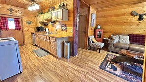 Een houten chalet van binnen met een keuken, eethoek en woonkamer.