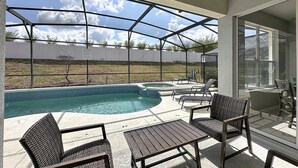 Ein überdachter Außenbereich mit Pool, Liegestühlen und einem Tisch.