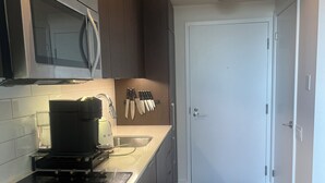 Eine moderne Küche mit integriertem Mikrowellenherd, Kaffeemaschine und einem Messerblock an der Wand.