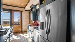 Eine moderne Küche mit Edelstahlgeräten, Holzschränken und einem großen Fenster mit Blick ins Freie.