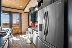 Eine moderne Küche mit Edelstahlgeräten, Holzschränken und einem großen Fenster mit Blick ins Freie.