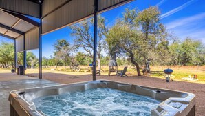 Ein Whirlpool mit Blick auf eine natürliche Landschaft, einschließlich Bäume und einem Grill.