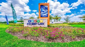 A sign for Storey Lake with a tropical mural, surrounded by a landscaped garden with pink flowers. - Storey Lake Magic - Five Bedroom Villa, Sleeps 10 (Kissimmee)