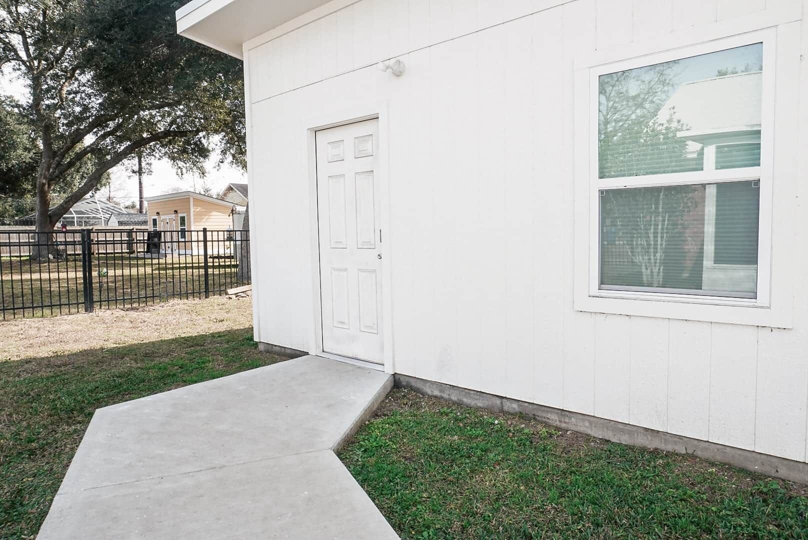 A white building with a single door and a window.