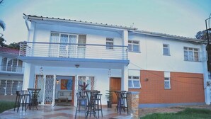 A two-story house with a balcony, a patio with chairs, and a gate. - Kololo 3BR with Garden, 500m to Acacia Mall (Kampala)