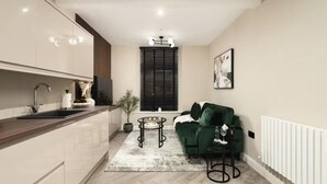 A modern kitchen with a wooden countertop and a sink, a green sofa, a small round table, and a potted plant. - City Centre Apartment Sleeps 2 With Wifi (Edinburgh)