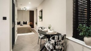 A modern dining area with a table set for two, a black and white patterned chair, and a window with blinds. - City Centre Apartment Sleeps 2 With Wifi (Edinburgh)