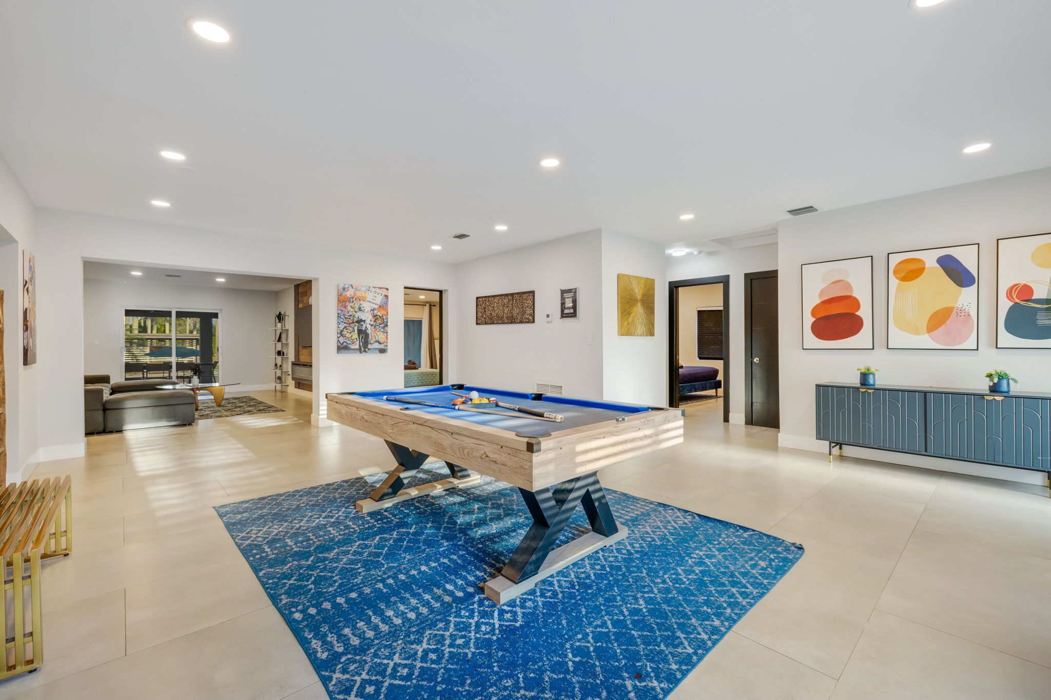 A spacious room with a pool table, a sofa, and a dining area.