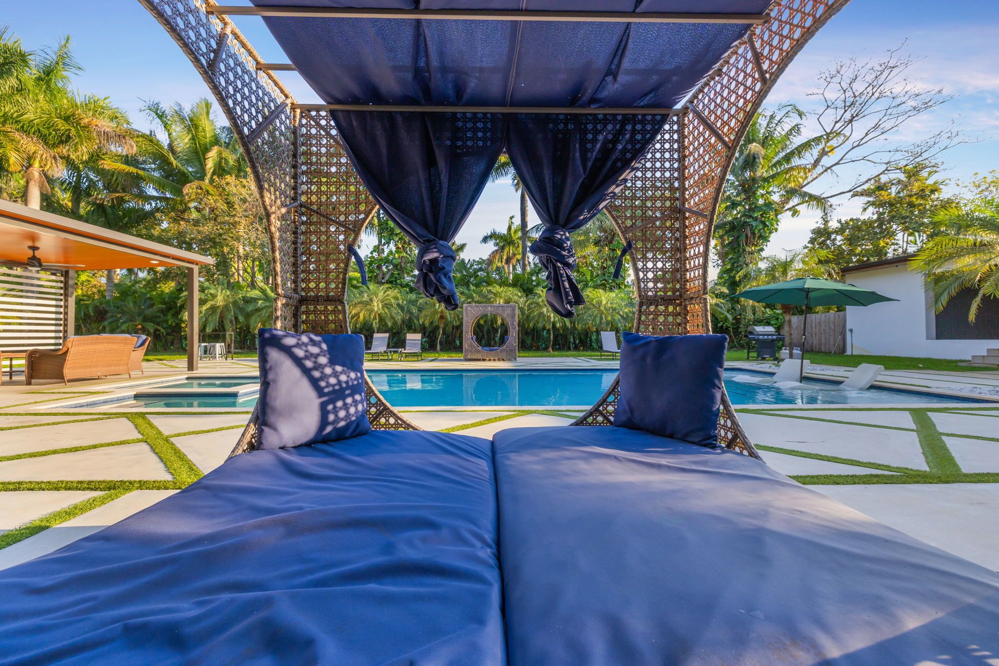 Ein Poolbereich mit Liegestühlen, einer Pergola mit Vorhängen und einem Pool.