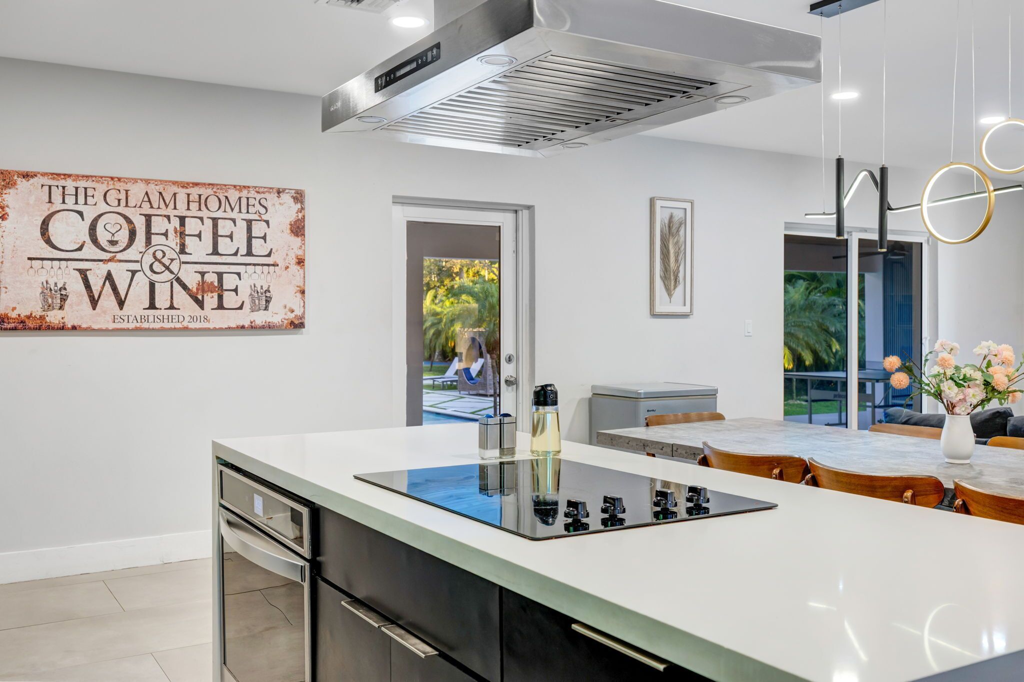 A modern kitchen with a central island, stainless steel appliances, and a coffee-themed wall sign.