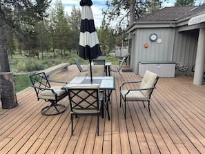 A deck with outdoor furniture, a clock, and a hot tub.