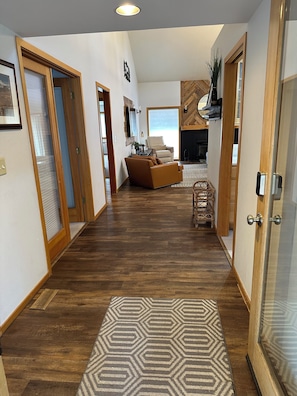 A hallway with wooden flooring, a patterned rug, a sofa, and a door with a handle.