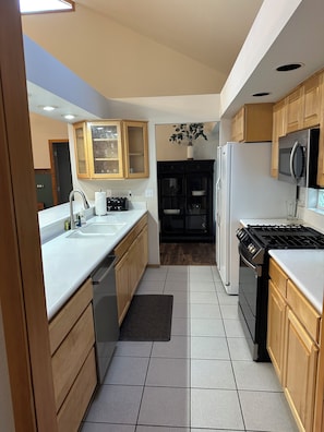 A kitchen with wooden cabinets, a stainless steel refrigerator, a stove, and a microwave.