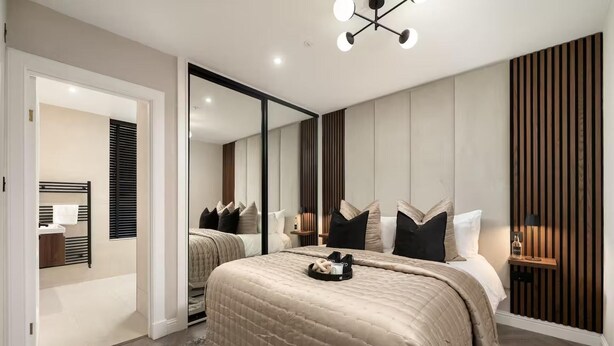 A modern bedroom with a large bed, a walk-in closet, and a mirror. - Edinburgh Apartment - Sleeps 2 - Princes St Close (Edinburgh)