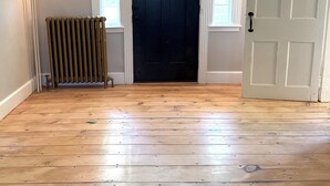 A hallway with a black door, white trim, and a radiator.