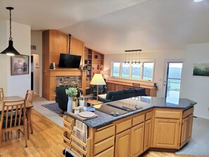A modern kitchen with wooden cabinets, a built-in island, a flat-screen TV, and a dining area with chairs. - Lookout- epic views, close to OSU, quiet (Corvallis)