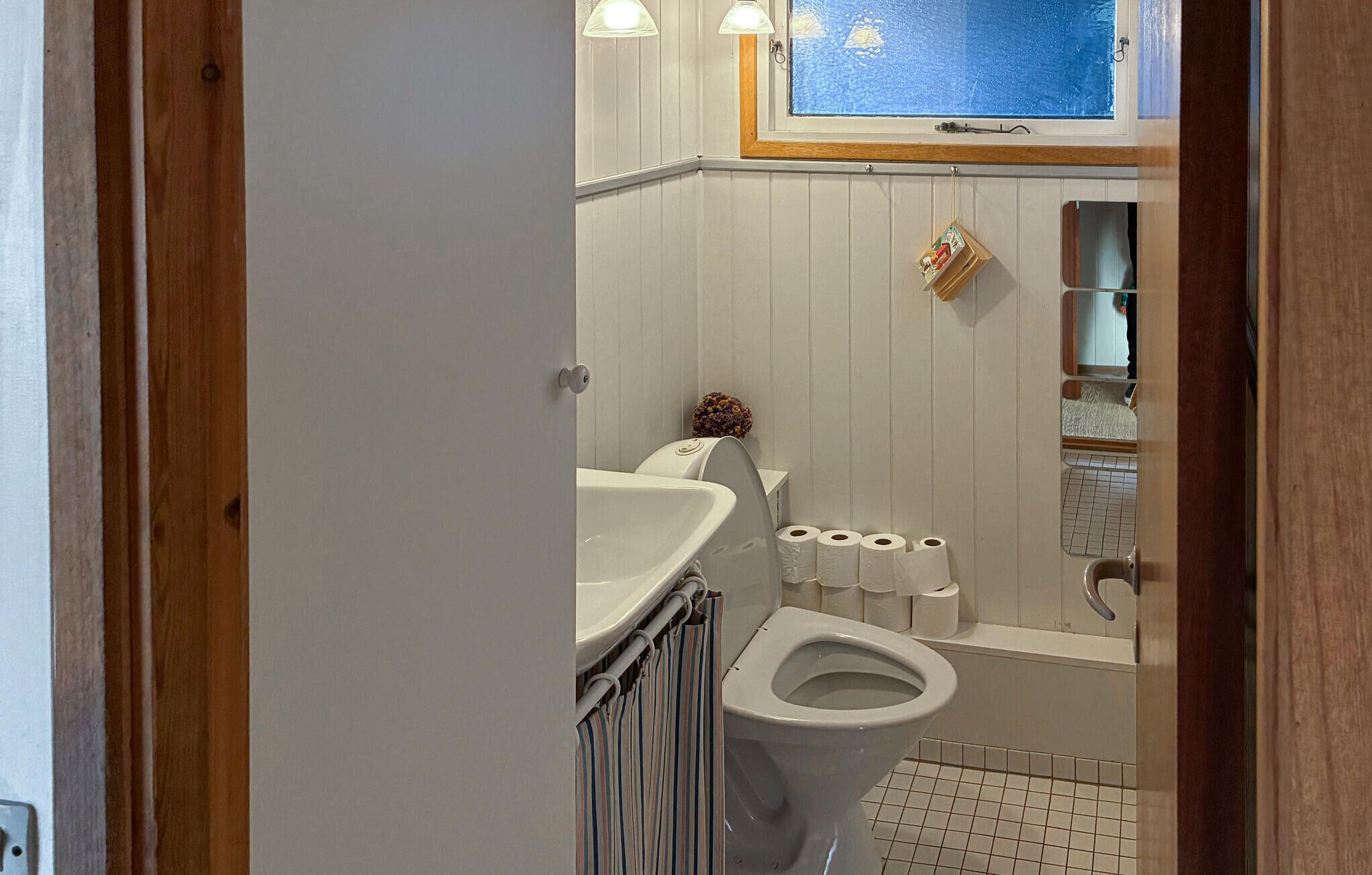 A bathroom with a toilet, sink, and a window above the sink.