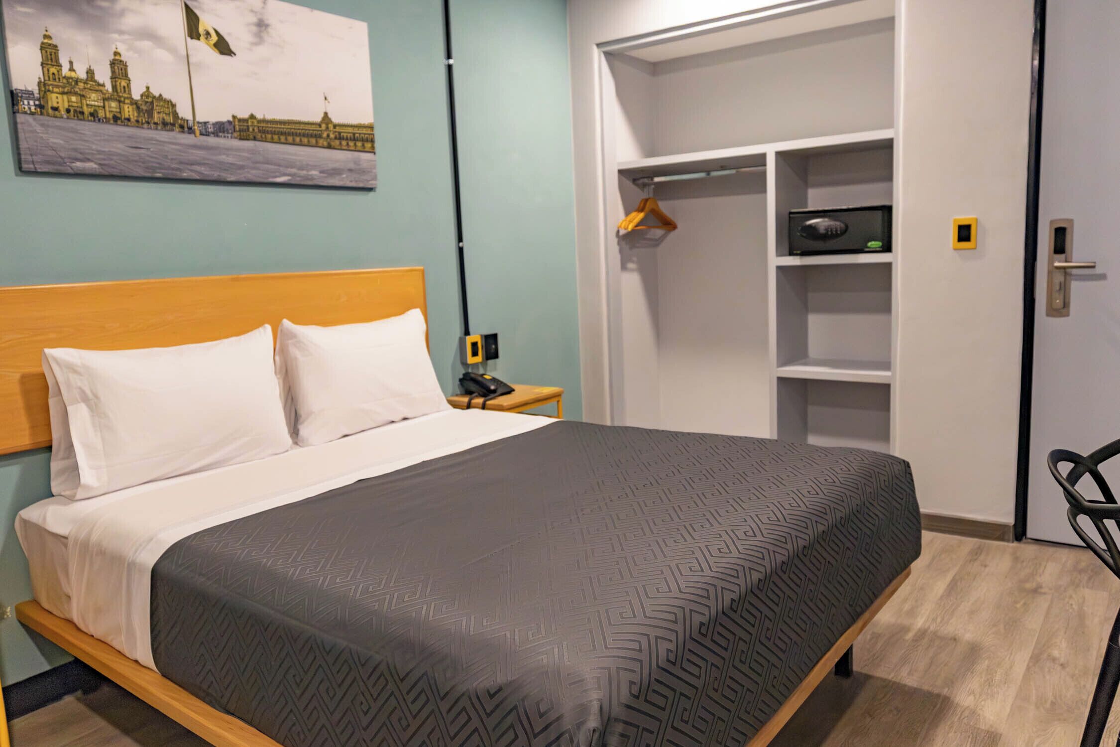 Une chambre d’hôtel avec un lit, une table de chevet, une armoire et un tableau au mur.