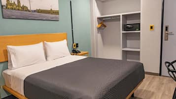 Une chambre d’hôtel avec un lit, une table de chevet, une armoire et un tableau au mur.
