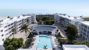 A hotel with a central pool, multiple balconies, and a view of the beach. - Island Beach Club 240F | Exquisite Oceanfront Residence | Sun, Sea and Sand (Sanibel)