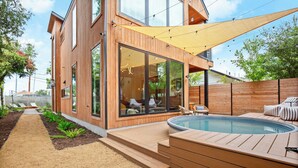Ett modernt hus med en träfasad, stora glasfönster, en swimmingpool och en uteplats.