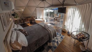 A spacious bedroom with a large bed, a desk, and a view of the outdoors.